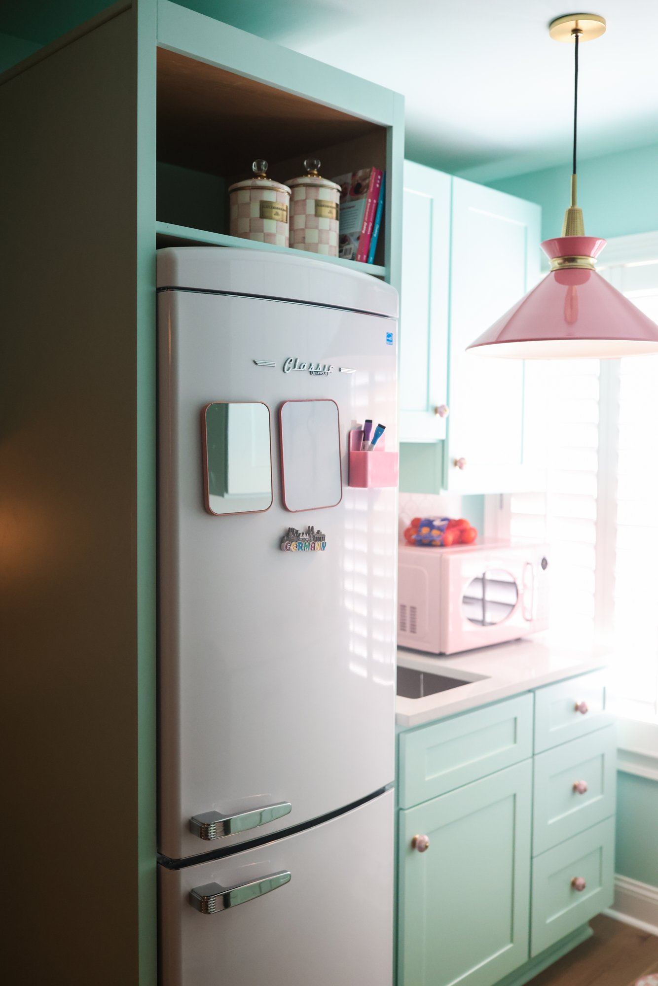 Playroom mini kitchen with a retro fridge, pink microwave, and pink pendant light