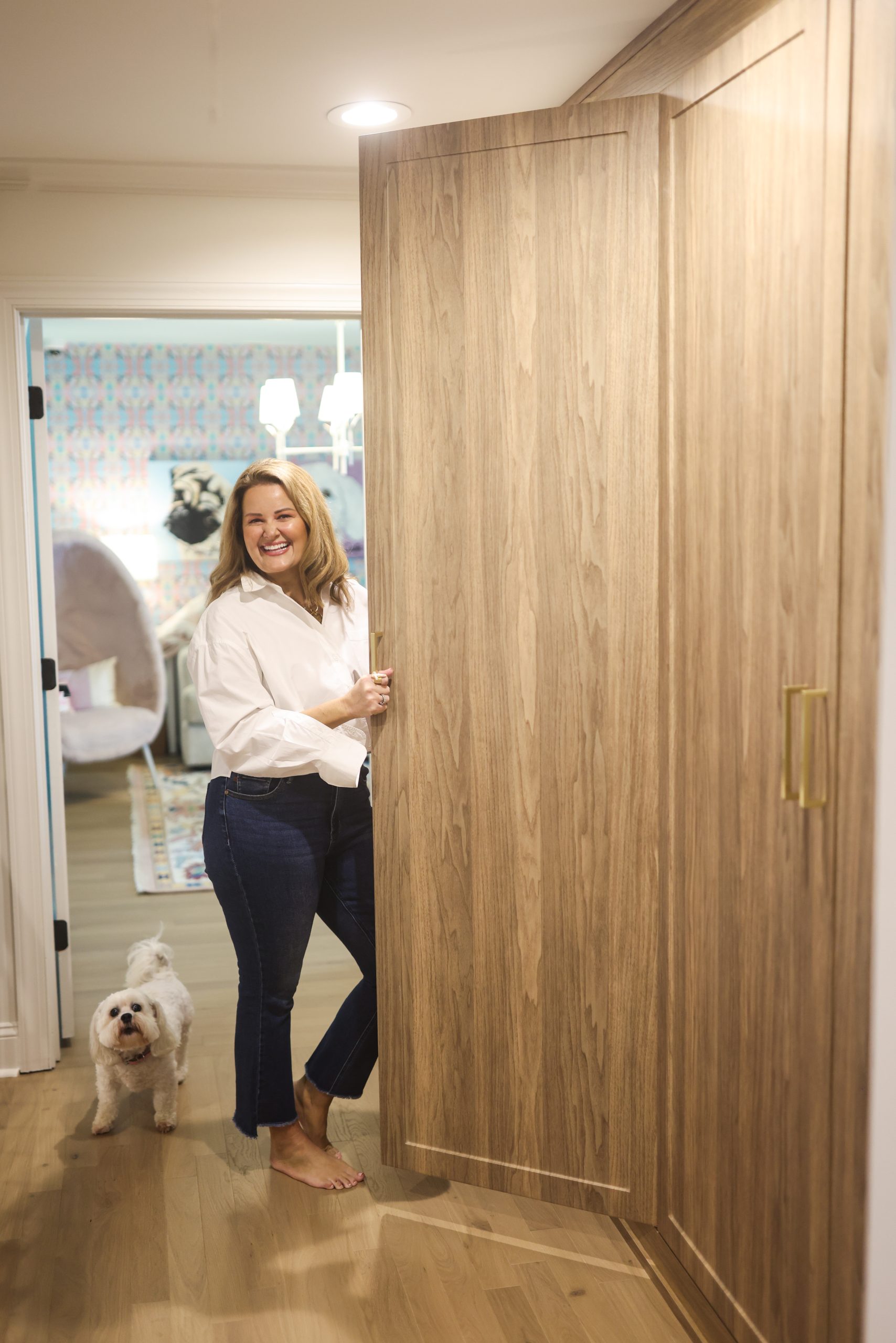 Mollie in the hallway off the foyer, opening a wood-paneled door with her dog by her side