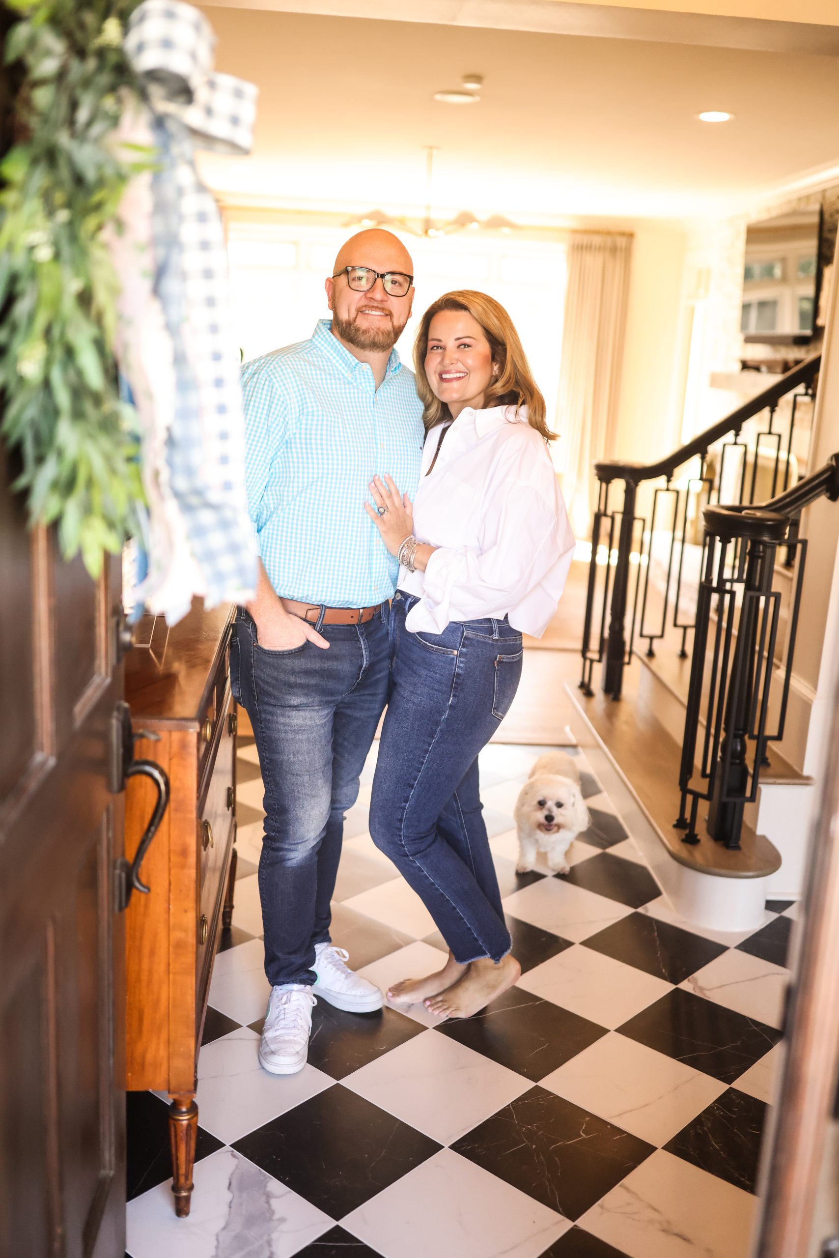 Mollie and her husband greeted by their dog in the checkered-tile foyer of their renovated home