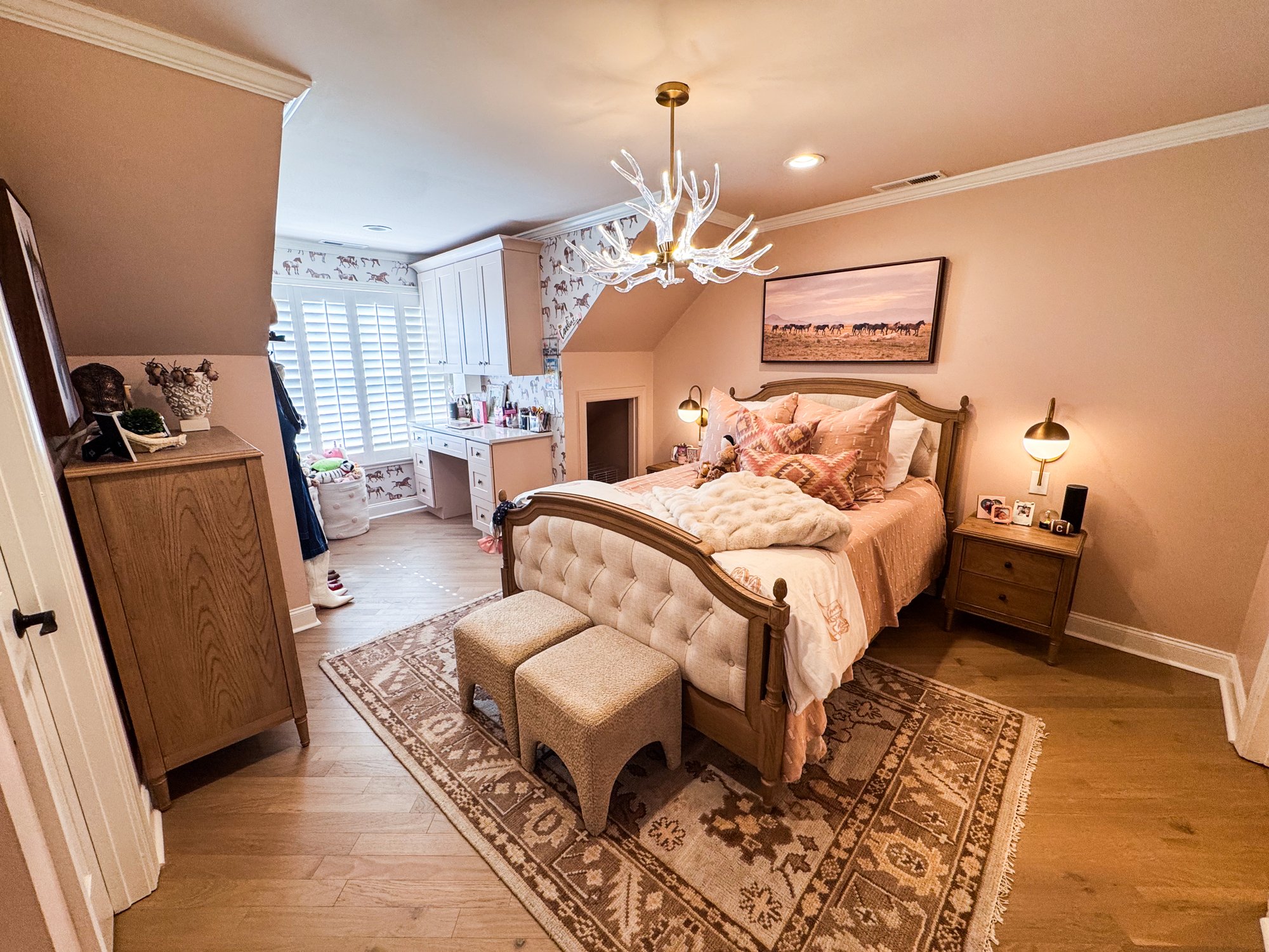 Caroline's bedroom with an acrylic antler chandelier, horse wallpaper, and a tufted upholstered bed