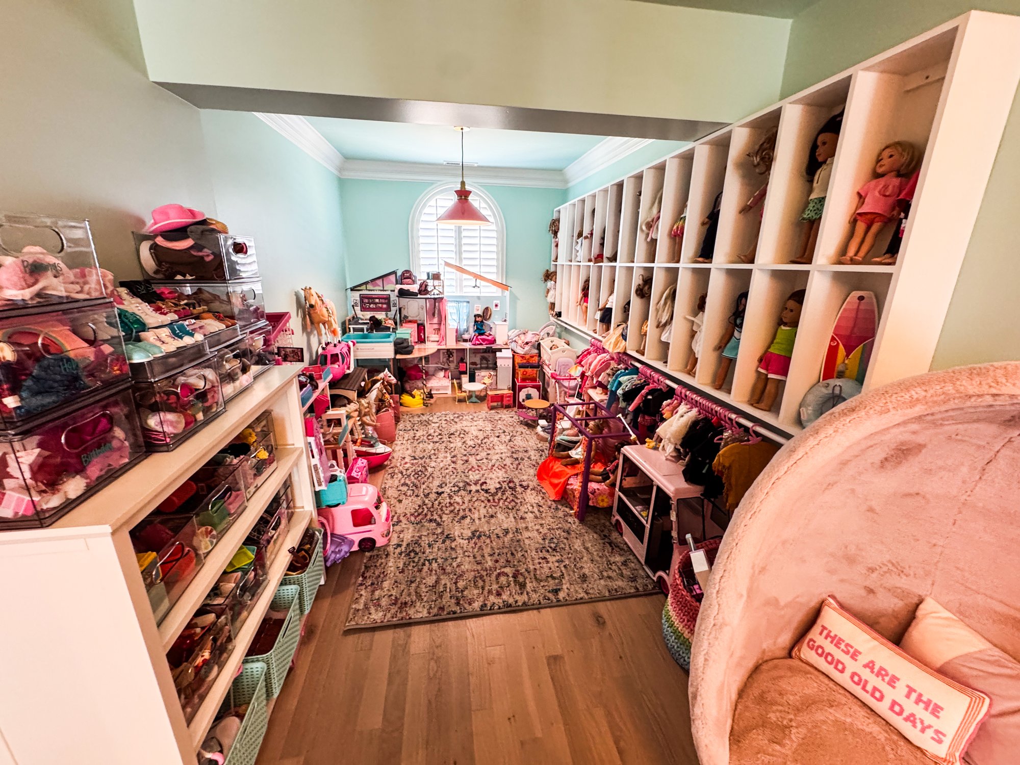 Long playroom with cubbies displaying American Girl dolls along one wall