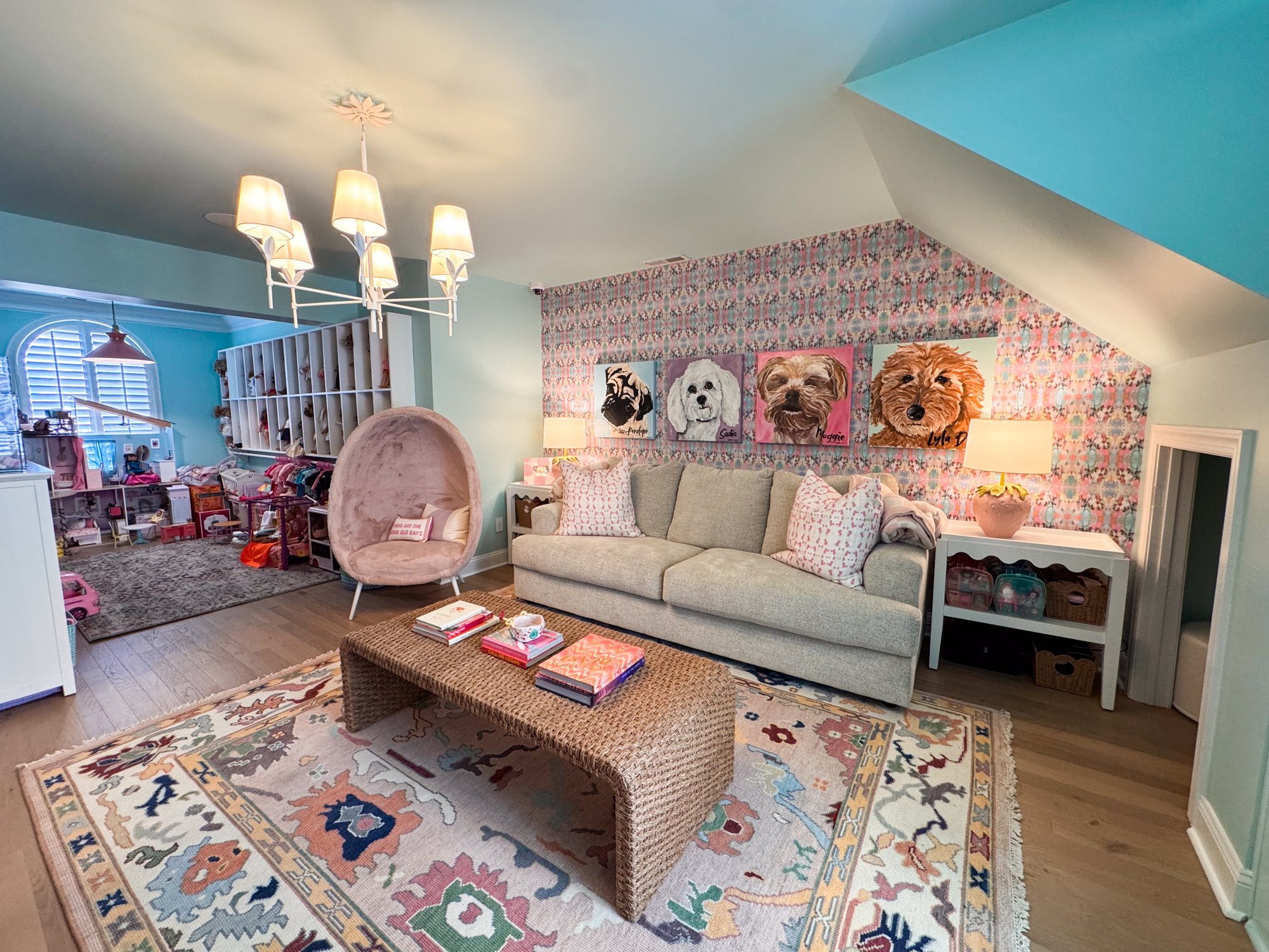 Playroom lounge zone with a gray sofa, woven coffee table, and chandelier