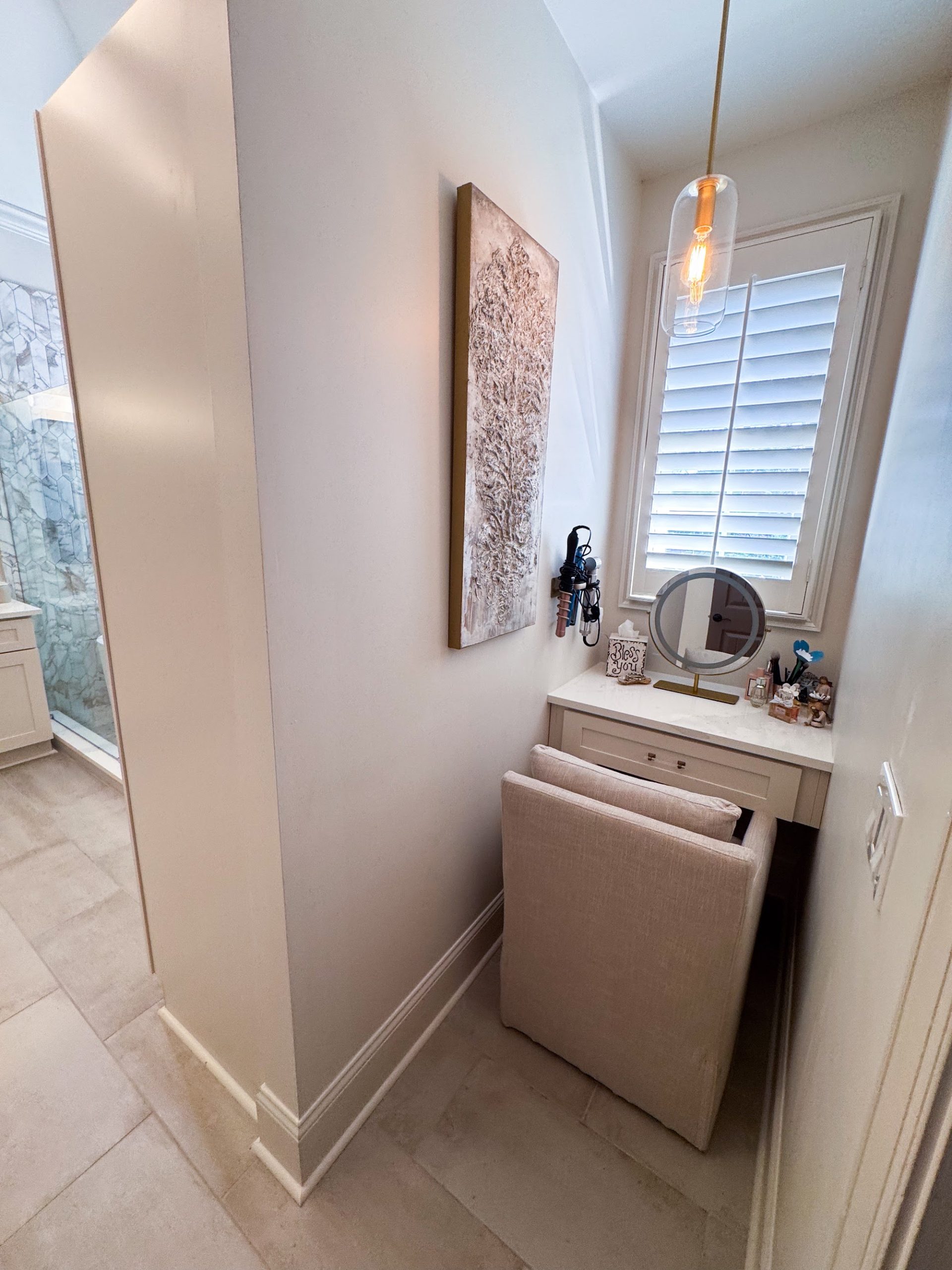 Built-in makeup station nook with a pendant light, mirror, and window seating in the primary bathroom